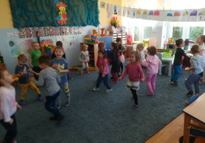 Dzieci tańczą na dywanie.